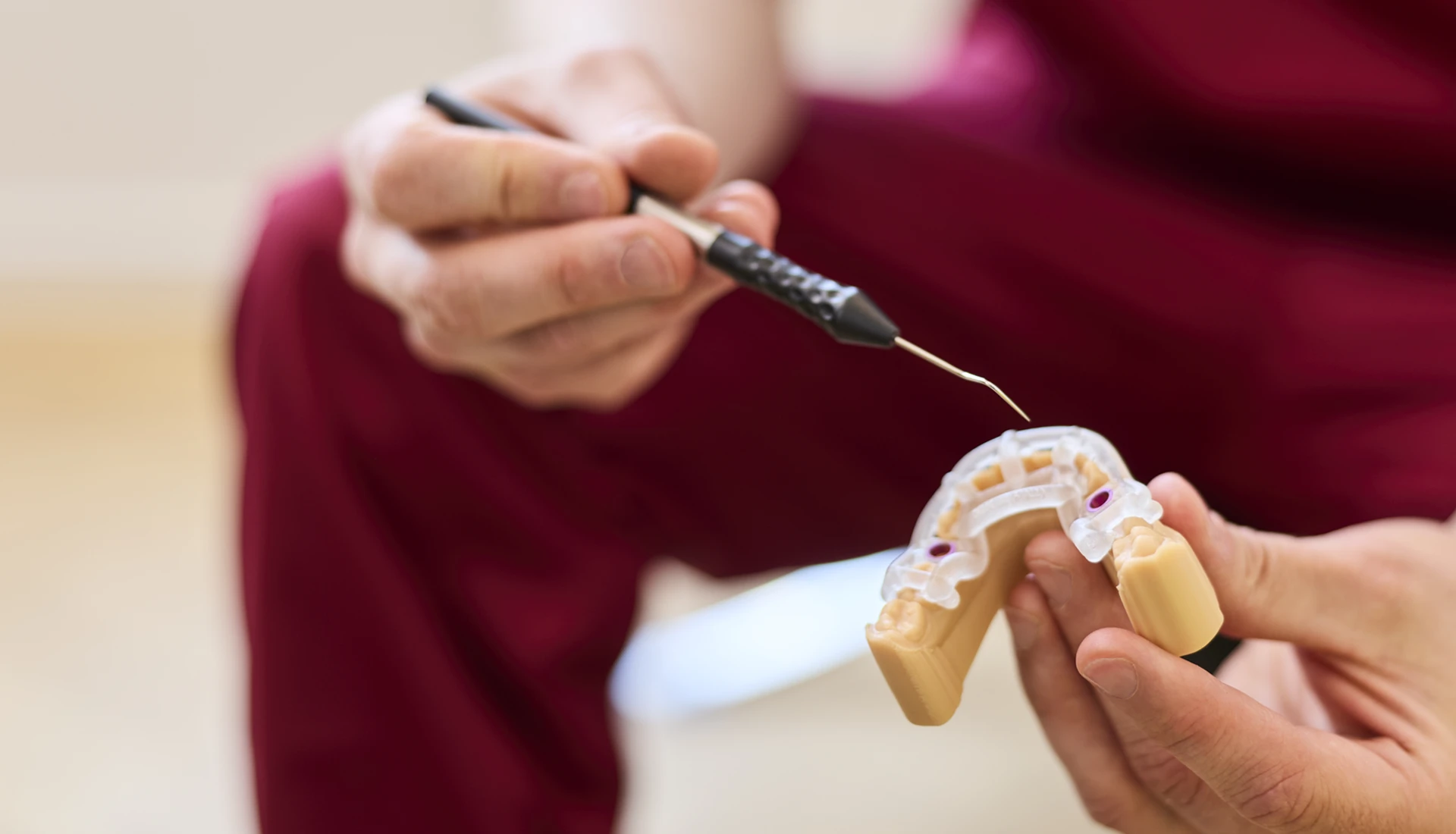 Fachzahnarzt Philipp Deuringer zeigt mit Zahnsonde auf eine Bohrschablone zum Thema 3d-navigierte Implantation.