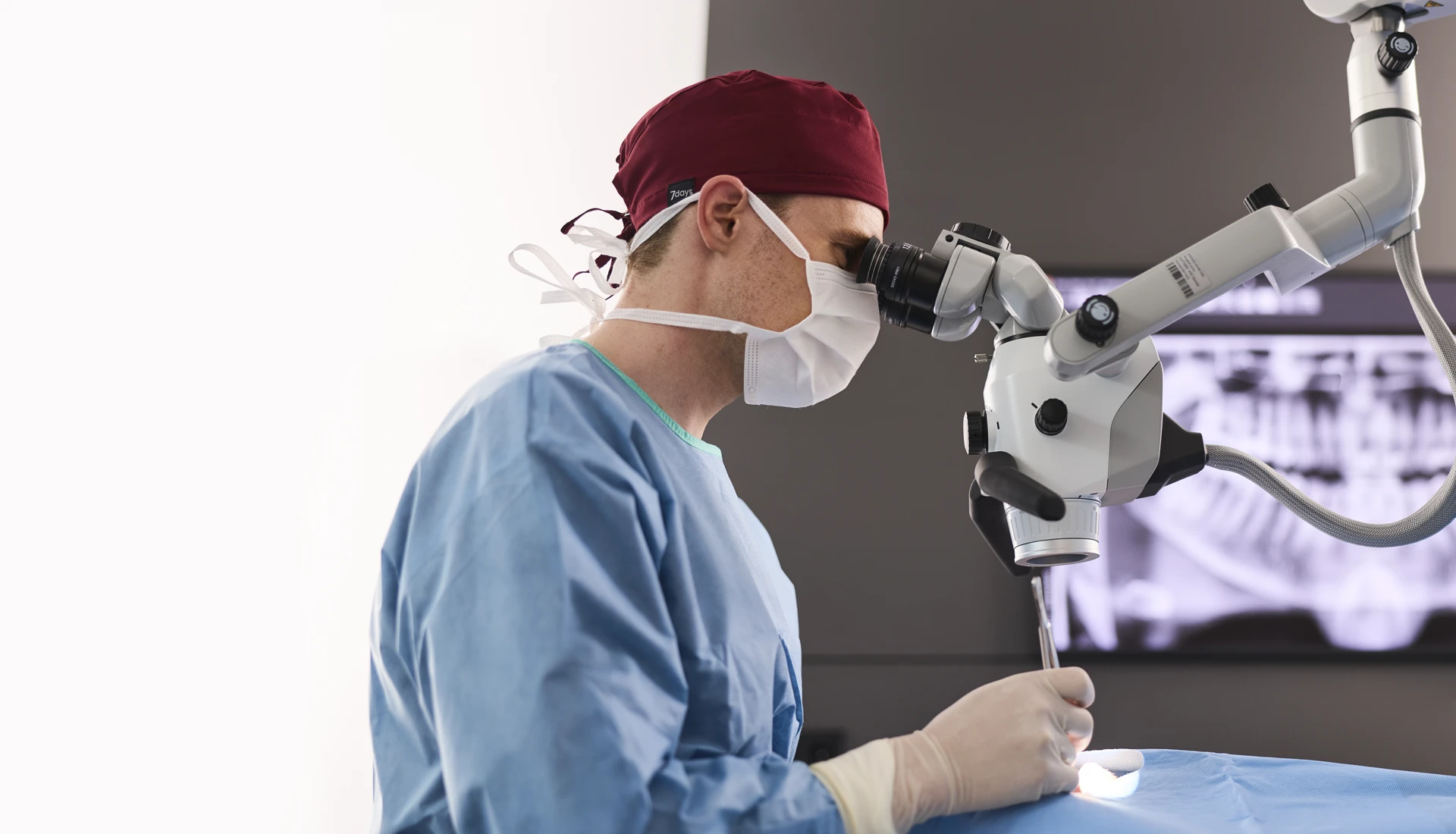Fachzahnarzt führt eine mikroskopische Wurzelspitzenresektion am Dentalmikroskop durch.