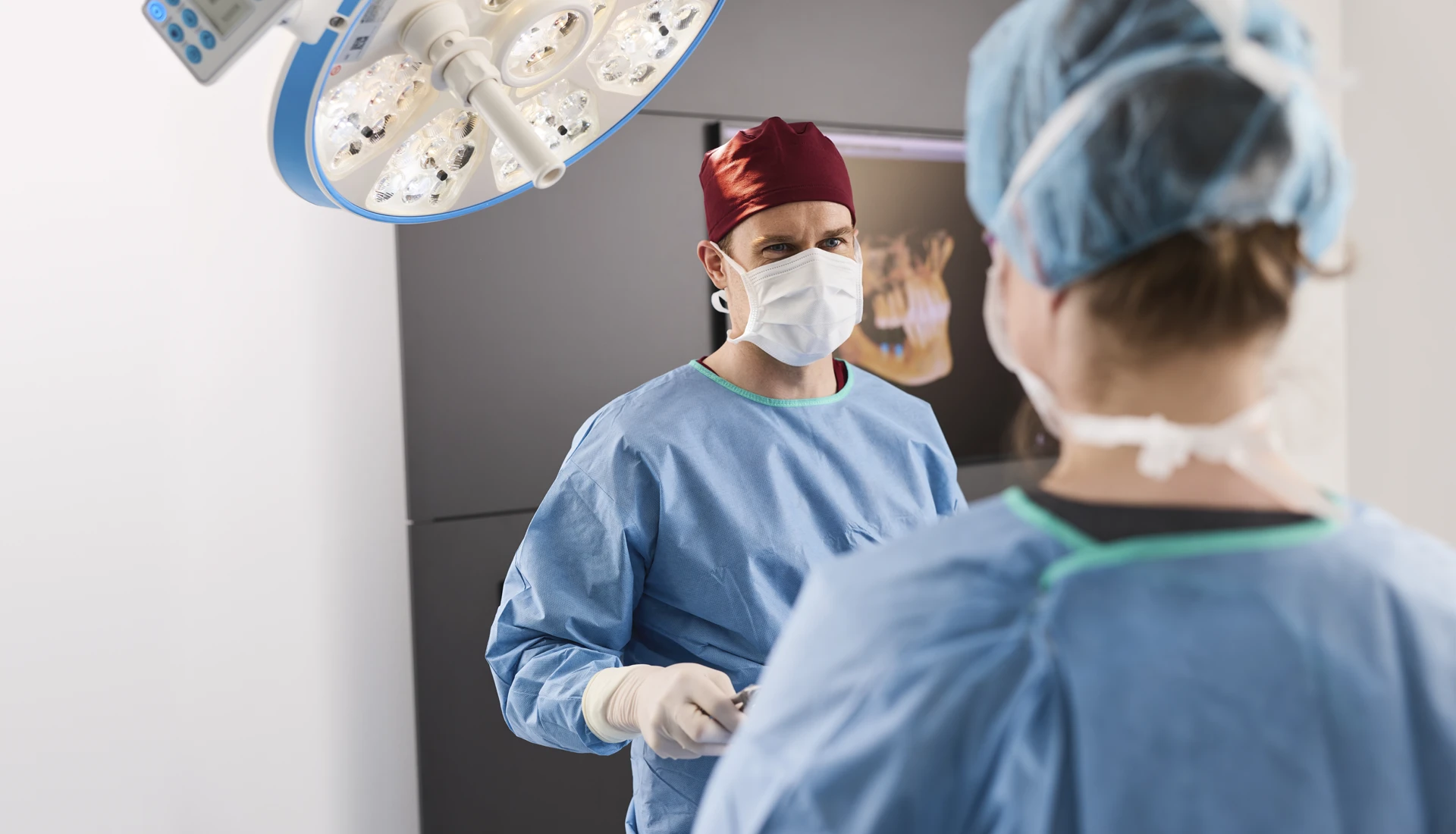 Fachzahnarzt und Assistenz im OP während einer Behandlung – der Blick des Zahnarztes ist auf die Assistenz gerichtet.